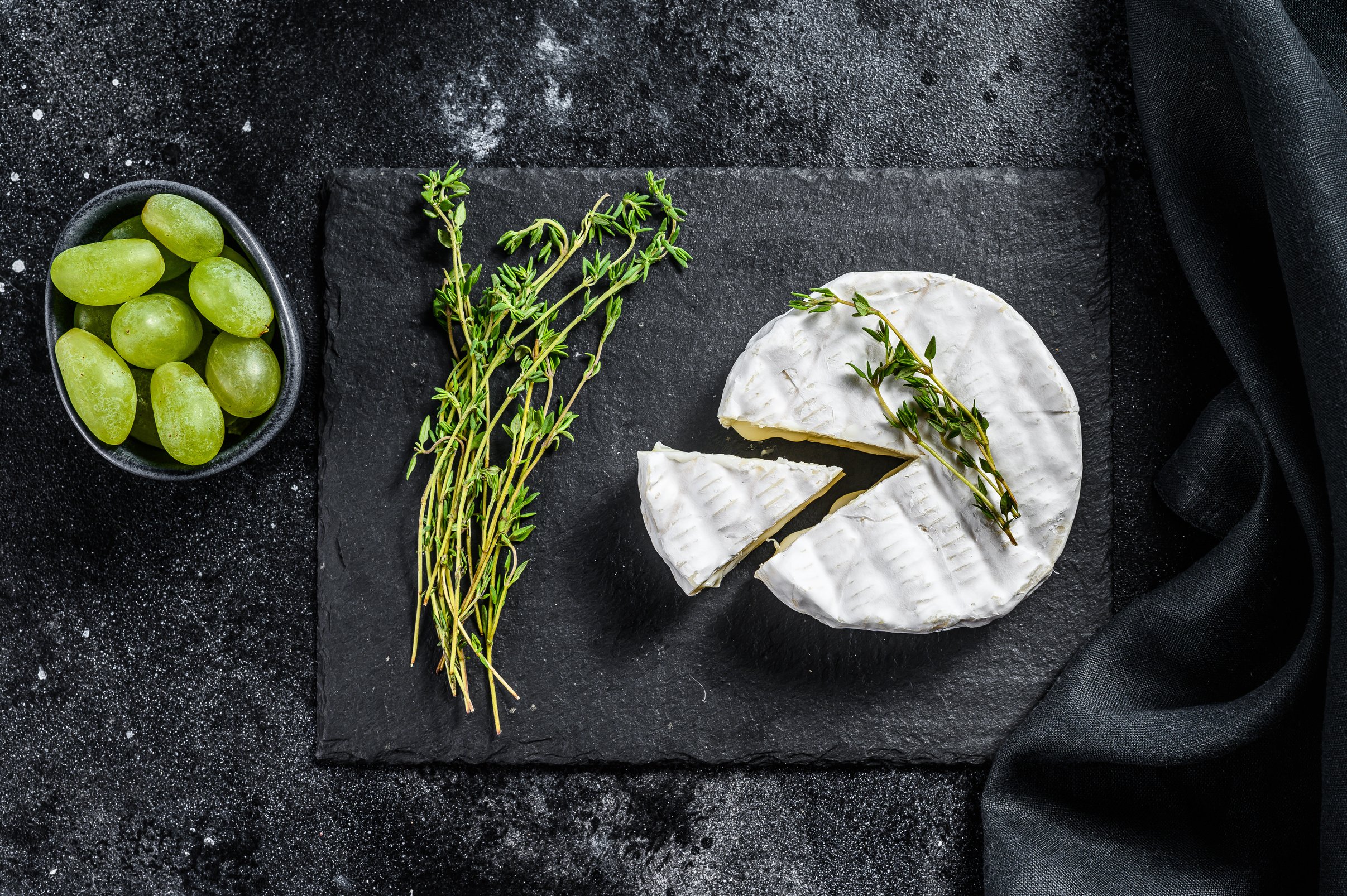 French Camembert Cheese with Grapes. Black Background. 